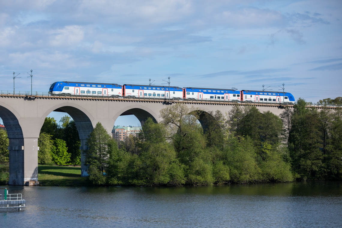 A Mälartåg double decker crossing a lake on an arch bridge.